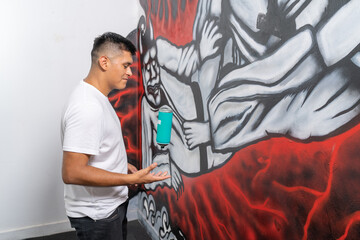 Muralist playing with a spray facing a new graffiti