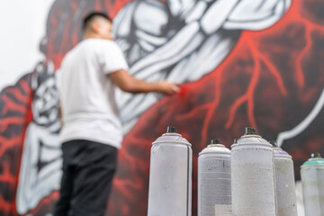 Sprays on the floor while a muralist painting a wall