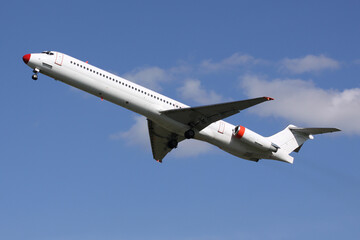 White Passenger Airplane with Red Nose Taking Off against Clear Blue Sky Background