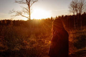 Young woman walking alone in forest enjoying sunset