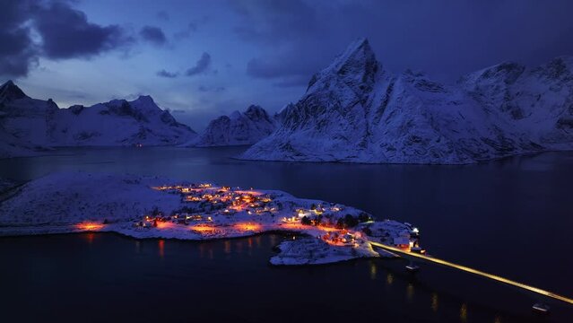 Drone Shot Captures the Snowy Mountains, Rorbuer, and Fjords Under the Starlit Night Sky in Lofoten Islands, Norway.
