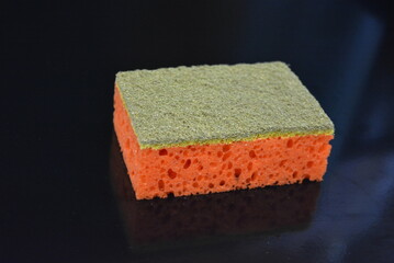 Things that are often used in the household. Colored washcloths for washing dishes are arranged on a glossy black background.