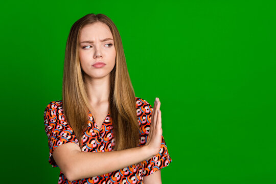 Photo of serious girl with straight hairdo dressed print shirt palm showing stop look empty space isolated on green color background