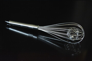 Home furnishings, a metal whisk for whipping egg whites and kneading dough arranged on a black...