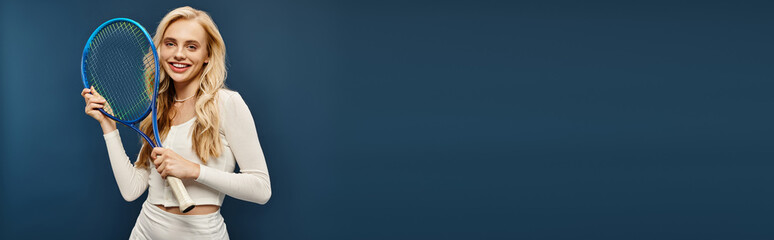 joyful blonde woman in white stylish outfit posing with tennis racquet on blue, horizontal banner
