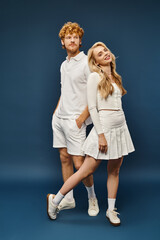 full length of aristocratic couple in white stylish clothes back to back on blue, classic fashion