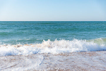 Waves in the sea near sandy shore. view of a waves in the sea near the beach. Summer holiday, clear azure water.