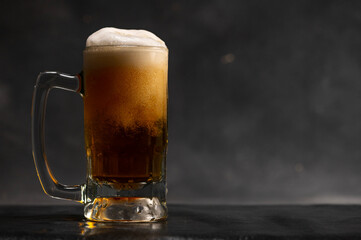 Craft beer with white froth in black background. Cold Beer glass mug with water drops with copy space