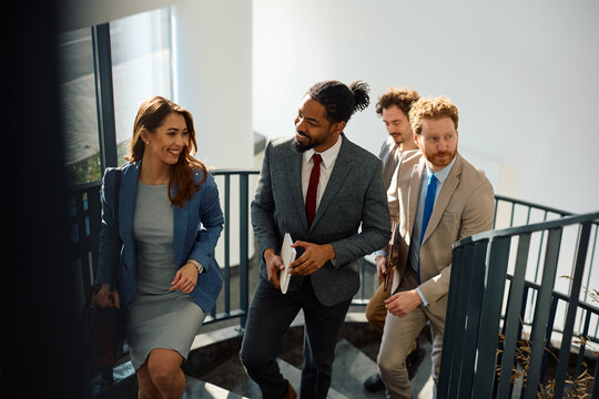 Group of diverse business people walking up the stairs in hallway.