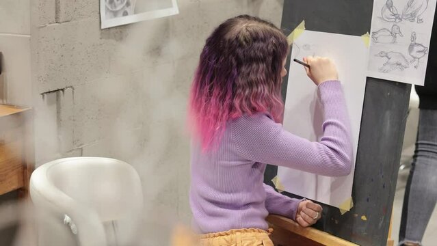Cute girl with pink hair painting on canvas, holding pencil, enjoying creative hobby, childhood, training artistic skills.