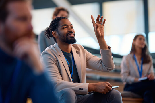 Happy black business seminar attendee asking question from audience.