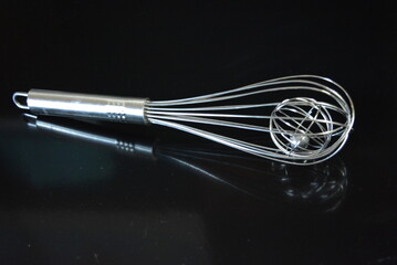 Home furnishings, a metal whisk for whipping egg whites and kneading dough arranged on a black...