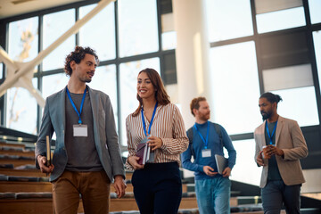Happy businessman talking to his female colleague after seminar in conference hall.