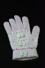 Clothing, women's wool pink white glove with bows arranged on a black glossy background.