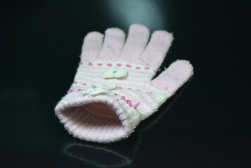 Clothing, women's wool pink white glove with bows arranged on a black glossy background.