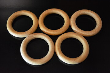 Interior items, wooden curtain rings placed on black glossy background.