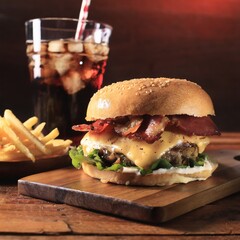 Tasty cheeseburger bacon with fries and soda on the table	