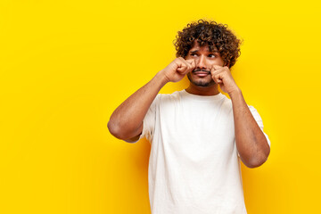 unhappy indian man crying and sad on yellow background, young offended guy in depression and stress...