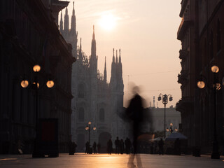view of Milan city in the morning sunrise with motion blurred people walking in piazza Duomo,...
