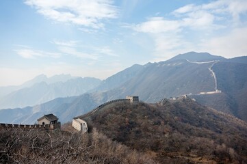 panoramic view of the Great Wall of china stretching out over the mountain terrain with blue skies in winter