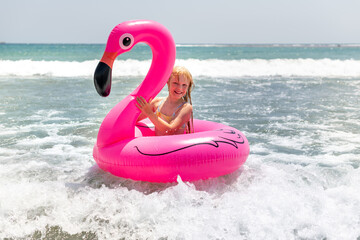 сhild playing in the water on a pink flamingo circle