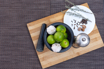 Ingredients for making a sauce based on garlic, lemons, thyme, cloves and nutmeg, made with a mortar on a kitchen board