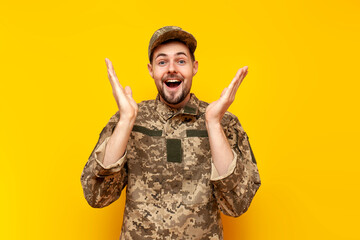 shocked Ukrainian army soldier in camouflage pixel uniform looks surprised and raises empty hands...