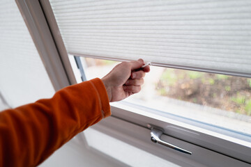 Hand holding the handle of made to measure conservatory blinds that slide up and down. Shallow focus. - 740307763