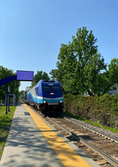 Locomotive head of a train on the railway. City train at the station ready for departure. Suburban train arrival at the boarding platform. Display panel for travel times. 