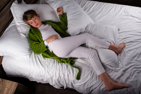 Male child wearing full length pajamas and robe sleeping alone in a bed - Powered by Adobe