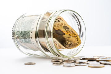 Polish zloty banknotes and coins in glass jar on a white background. Saving money concept on a white background