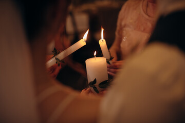 Several tall candles were lit in the dark church. Banquet, restaurant. Table setting. Many tall candles in a dark room, white and tall standing candles with flames