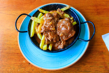 Iberian pork cheeks stew with potatoes on wooden table. Top view
