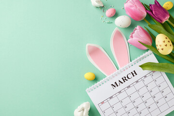 Easter festivity: calendar countdown and spring blooms. Top view shot of bunny ears, March calendar, decorated eggs, tulips, candy sprinkles on teal background with space for notes or reminders