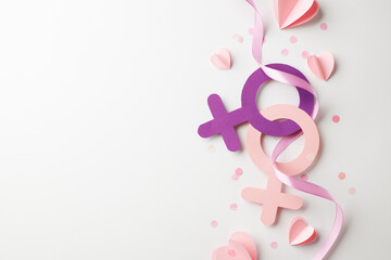 Diversity in unity: the essence of female empowerment. Top view shot of pink and purple female gender symbol surrounded by a swirl of ribbon, hearts, confetti on white background with space for advert - obrazy, fototapety, plakaty