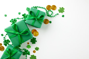 St. Patrick's Day surprises: treasures at the end of the rainbow. Top view shot of green gift boxes with satin ribbons, shamrock confetti, gold coins on white background with space for advert