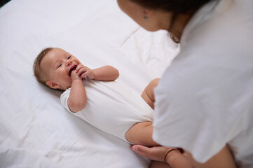 Authentic mother takes care of her smiling baby boy 4 months old, feeling emotional connection. Maternity leave. Infancy