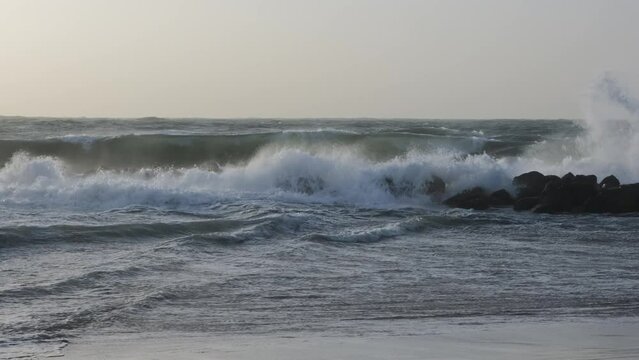 Large waves in the Mediterranean Sea crash against the rocks, depicting a scene of stormy weather at sea.