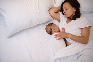 The concept of co-sleeping and breastfeeding. View from above of a sleeping mother breastfeeding...