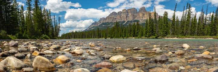 Summer time stunning views at Castle Mountain in Banff National Park with views along the turquoise Bow River in Alberta. Beautiful blue sky day with clouds.  - obrazy, fototapety, plakaty