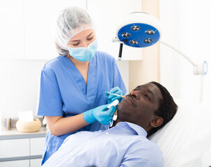 Fototapeta premium Afro american adult man patient of cosmetologist receiving hyaluronic acid injections in aesthetic clinic