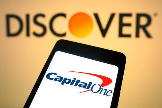 February 19, 2024, Brazil. In this photo illustration, the Capital One Financial logo is displayed on a smartphone screen with the logo Discover Financial Services in the background