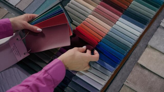 Close up details fabric swatches different trend colors sample collection on table unrecognizable woman customer comparing color shades touching upholstery material for furniture and interior design