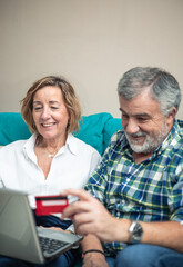 vertical portrait retired couple making online shopping with credit card