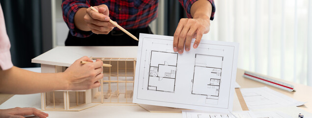 Cropped image professional architect hand compare construction between blueprint and house model...