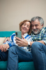 vertical portrait elderly couple relaxing at home with smartphone and headphones