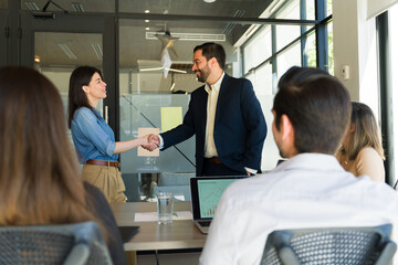 Businesspeople shaking hands in the middel of a meeting room