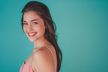 Smiling beautiful young woman in pink mini dress posing on turquoise background.