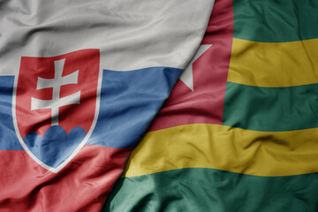 big waving national colorful flag of togo and national flag of slovakia .