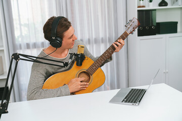 Host channel in smart singer with smiling face, playing guitar along singing, broadcasting on...